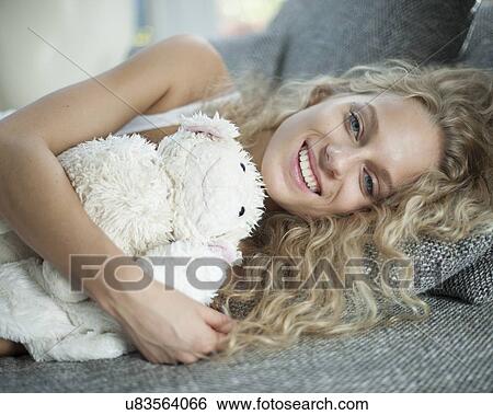 Portrait of young woman with teddy bear lying on sofa View Large Photo Image Stock Photograph - Portrait of young woman with teddy bear lying on sofa. Fotosearch