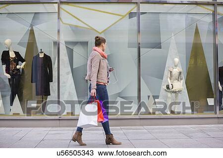 Profile shot of young woman with shopping bags looking at window display View Large Photo Image Stock Image - Profile shot of young woman with shopping bags looking at window display. Fotosearch