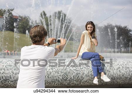 Rear view of man videotaping woman against fountain View Large Photo Image Picture - Rear view of man videotaping woman against fountain. Fotosearch