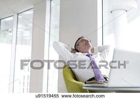 Stock Photography - Relaxed mature businessman reclining at lobby. Fotosearch