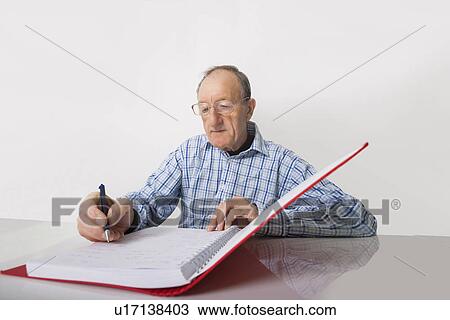 Senior businessman writing in file at desk View Large Photo Image Stock Image - Senior businessman writing in file at desk. Fotosearch