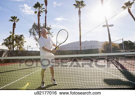 Stock Photograph - Senior male tennis player holding racket on court. Fotosearch