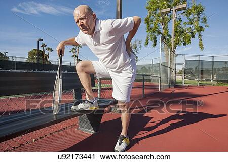 Senior male tennis player with back pain on court View Large Photo Image Stock Image - Senior male tennis player with back pain on court. Fotosearch