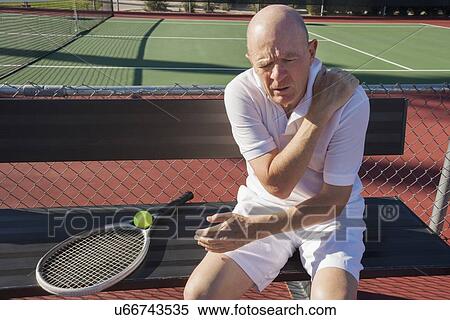 Senior male tennis player with shoulder pain sitting on bench at court View Large Photo Image Stock Photography - Senior male tennis player with shoulder pain sitting on bench at court. Fotosearch