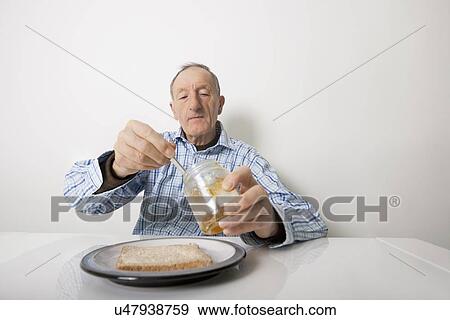 Senior man preparing slice of bread and marmalade at table View Large Photo Image Stock Photo - Senior man preparing slice of bread and marmalade at table. Fotosearch