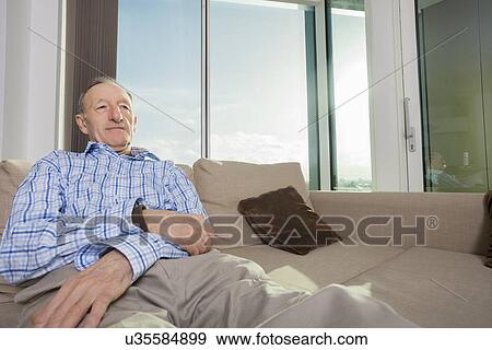 Senior man relaxing on sofa at home View Large Photo Image Stock Photo - Senior man relaxing on sofa at home. Fotosearch