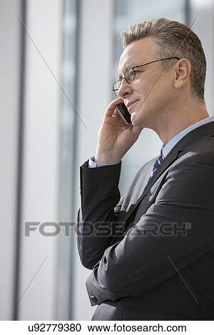 Side view of businessman using cell phone in office View Large Photo Image Stock Image - Side view of businessman using cell phone in office. Fotosearch