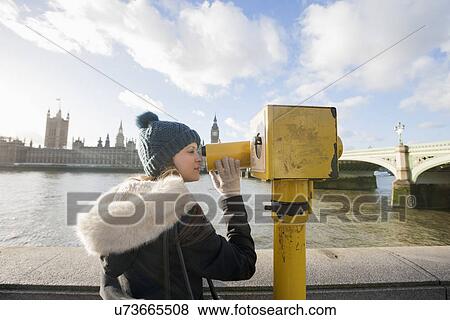 Side view of young woman looking through telescope by river Thames, London, UK View Large Photo Image Stock Photo - Side view of young woman looking through telescope by river Thames, London, UK. Fotosearch