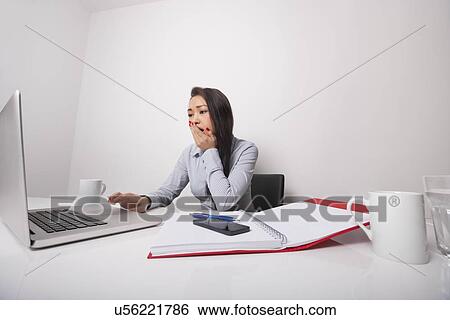 Sleepy businesswoman working on laptop at office desk View Large Photo Image Stock Photograph - Sleepy businesswoman working on laptop at office desk. Fotosearch