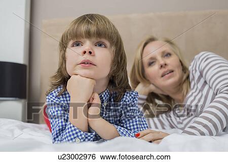 Stock Photograph - Thoughtful boy with mother in bed. Fotosearch