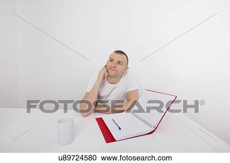 Thoughtful businessman answering smart phone at desk View Large Photo Image Stock Image - Thoughtful businessman answering smart phone at desk. Fotosearch