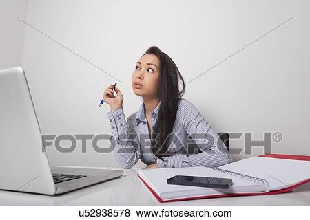 Thoughtful businesswoman sitting at office desk View Large Photo Image Stock Photo - Thoughtful businesswoman sitting at office desk. Fotosearch