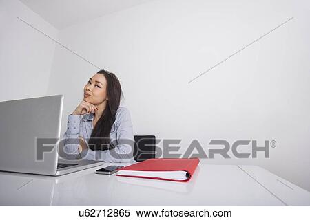 Stock Photography - Thoughtful businesswoman sitting at office desk. Fotosearch