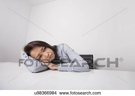 Picture - Tired businesswoman leaning at office desk. Fotosearch