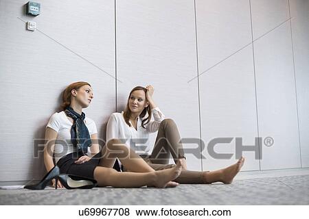 Tired businesswomen sitting on floor in office View Large Photo Image Stock Photo - Tired businesswomen sitting on floor in office. Fotosearch