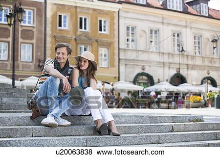 Tourist couple sitting on steps against building View Large Photo Image Stock Photo - Tourist couple sitting on steps against building. Fotosearch