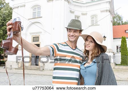 Picture - Tourist couple taking self portrait outside St. Casimir Church, Warsaw, Poland. Fotosearch