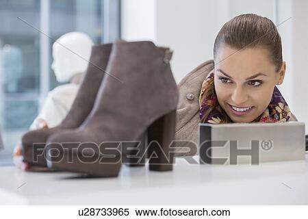 Stock Photography - Woman admiring footwear in store. Fotosearch