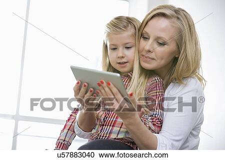 Woman using digital tablet with daughter at home View Large Photo Image Stock Image - Woman using digital tablet with daughter at home. Fotosearch