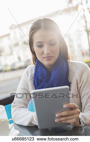 Stock Image - Woman using tablet PC at sidewalk cafe. Fotosearch