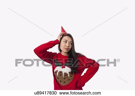 Woman wearing Christmas jumper and party hat against gray background View Large Photo Image Stock Image - Woman wearing Christmas jumper and party hat against gray background. Fotosearch
