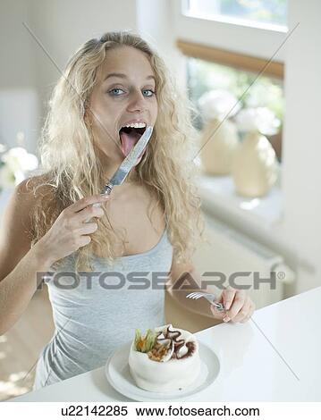 Woman with cake licking table knife at counter in house View Large Photo Image Stock Photography - Woman with cake licking table knife at counter in house. Fotosearch