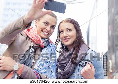 Women in jackets taking self portrait through mobile phone View Large Photo Image Stock Image - Women in jackets taking self portrait through mobile phone. Fotosearch