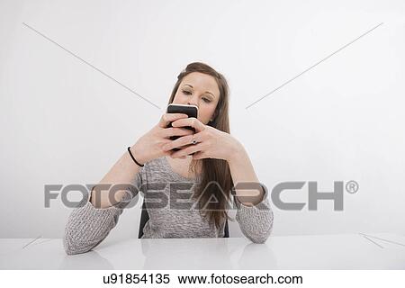 Young businesswoman text messaging on smart phone at office desk View Large Photo Image Stock Photography - Young businesswoman text messaging on smart phone at office desk. Fotosearch