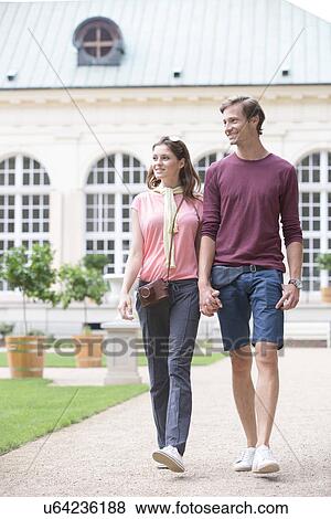 Young couple walking against buildings View Large Photo Image Stock Photo - Young couple walking against buildings. Fotosearch