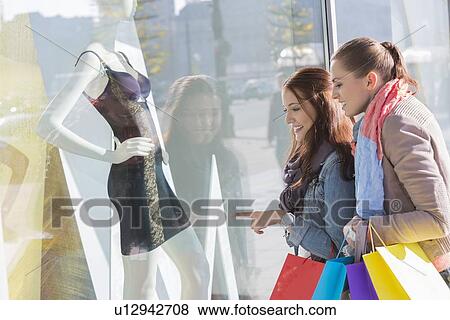 Young female friends window shopping View Large Photo Image Stock Photo - Young female friends window shopping. Fotosearch