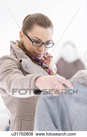Young woman analyzing sweater in store View Large Photo Image Stock Photo - Young woman analyzing sweater in store. Fotosearch