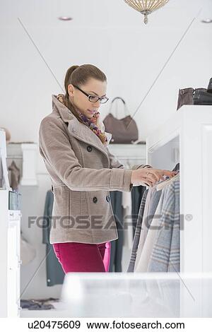 Young woman choosing sweater in store View Large Photo Image Stock Photo - Young woman choosing sweater in store. Fotosearch