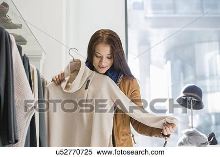 Young woman choosing sweater in store View Large Photo Image Stock Photography - Young woman choosing sweater in store. Fotosearch