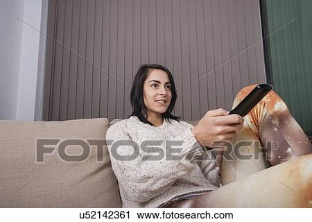 Young woman watching TV in living room View Large Photo Image Stock Image - Young woman watching TV in living room. Fotosearch