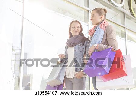 Young women carrying shopping bags by store View Large Photo Image Stock Photo - Young women carrying shopping bags by store. Fotosearch