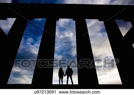 Stock Image - A young couple hold hands at the National Monument on Calton Hill in Edinburgh, Scotland. Fotosearch