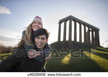 Stock Photo - A young couple on Calton Hill with the background of the National Monument of Scotland in Edinburgh. Fotosearch