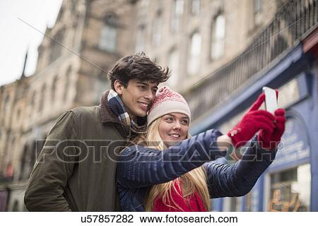 Stock Image - A young couple photograph themselves in the Grassmarket in Edinburgh, Scotland. Fotosearch