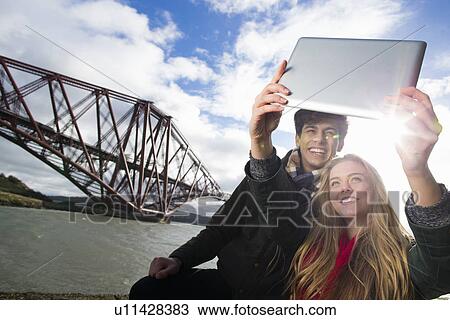 A young couple pose in front of the Forth Rail Bridge in Queensferry, near Edinburgh, Scotland View Large Photo Image Stock Image - A young couple pose in front of the Forth Rail Bridge in Queensferry, near Edinburgh, Scotland. Fotosearch