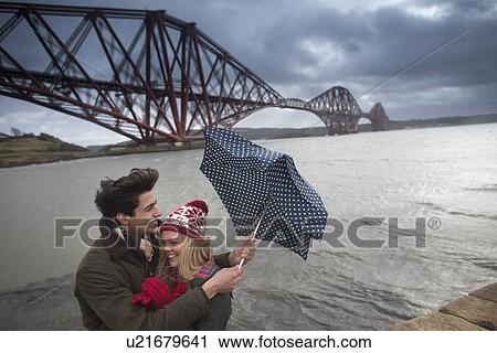 A young couple pose in front of the Forth Rail Bridge in Queensferry, near Edinburgh, Scotland View Large Photo Image Stock Image - A young couple pose in front of the Forth Rail Bridge in Queensferry, near Edinburgh, Scotland. Fotosearch