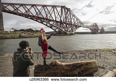 A young couple pose in front of the Forth Rail Bridge in Queensferry, near Edinburgh, Scotland View Large Photo Image Stock Photograph - A young couple pose in front of the Forth Rail Bridge in Queensferry, near Edinburgh, Scotland. Fotosearch
