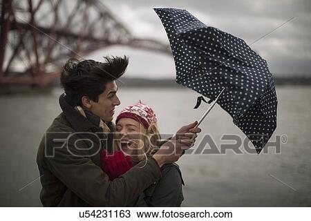 A young couple struggle with an umbrella in front of the Forth Rail Bridge in Queensferry, near Edinburgh, Scotland View Large Photo Image Stock Image - A young couple struggle with an umbrella in front of the Forth Rail Bridge in Queensferry, near Edinburgh, Scotland. Fotosearch