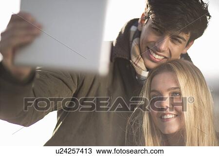 A young couple take self portrait photograph using digital tablet View Large Photo Image Stock Image - A young couple take self portrait photograph using digital tablet. Fotosearch
