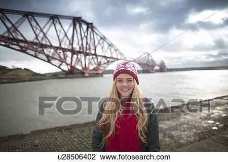 A young womans poses in front of the Forth Rail Bridge in Queensferry, near Edinburgh, Scotland View Large Photo Image Stock Image - A young womans poses in front of the Forth Rail Bridge in Queensferry, near Edinburgh, Scotland. Fotosearch