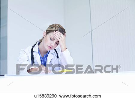 Stock Image - Anxious and overworked female doctor. Fotosearch