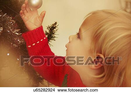 Picture - Baby girl looking at Christmas bauble. Fotosearch
