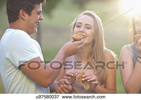 Boy feeding girl, friend in background View Large Photo Image Stock Photo - Boy feeding girl, friend in background. Fotosearch