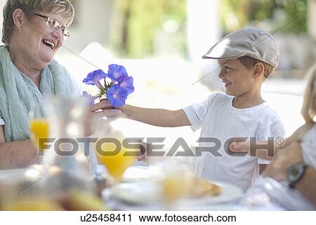 Boy giving flowers to grandmother View Large Photo Image Stock Image - Boy giving flowers to grandmother. Fotosearch