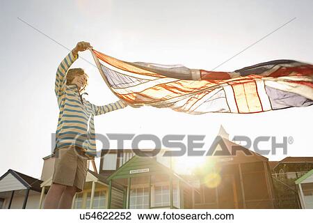 Stock Image - Boy holding up union jack flag at beach, Southwold, Suffolk, UK. Fotosearch