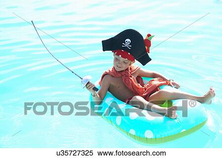 Boy lounging on rubber ring in pool dressed up as a pirate View Large Photo Image Stock Photography - Boy lounging on rubber ring in pool dressed up as a pirate. Fotosearch